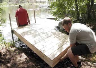 Two men removing a dock from the water and storing it away for the winter season